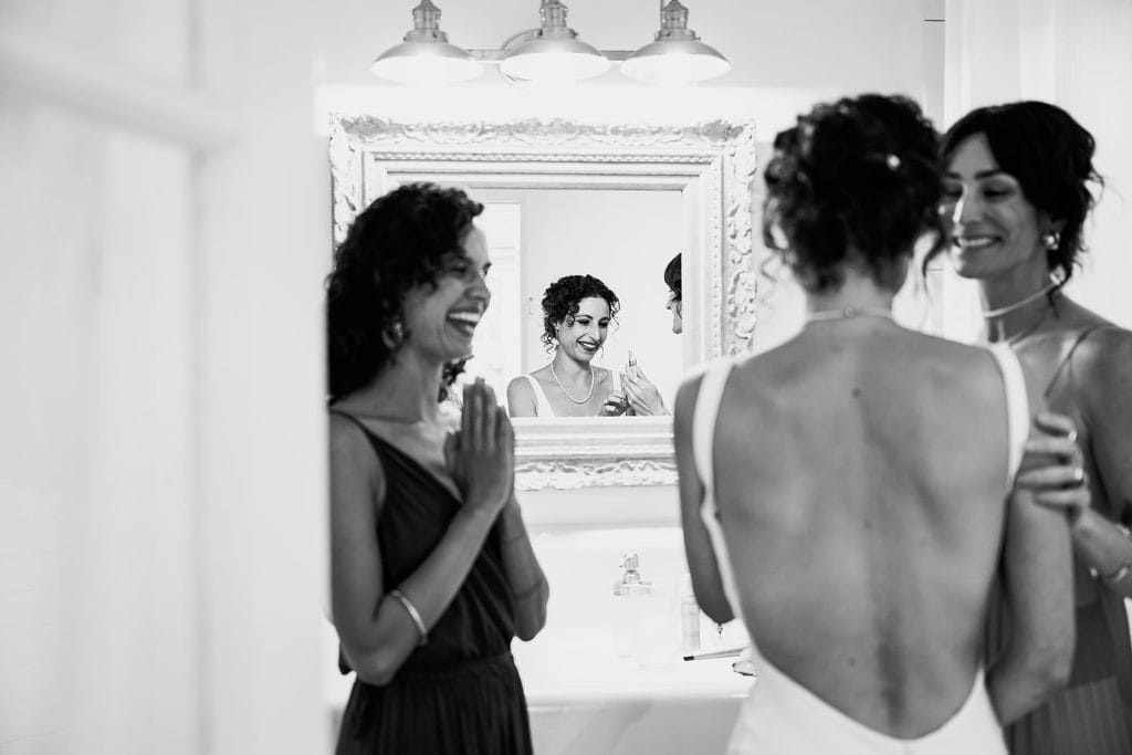 Bride with her bridesmaids doing her make up in the bathroom mirror I Clapton in country club in London