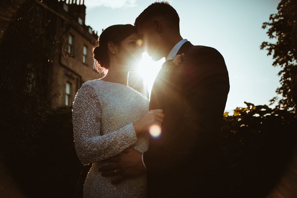 Editorial wedding portrait of a modern couple during golden hour in Bath, Somerset, showcasing the warm glow of sunset light on historic Georgian architecture.