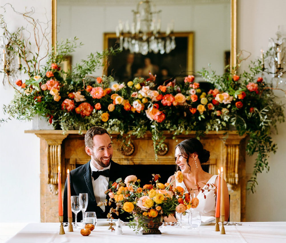 bride and grrom smiling at eachother with amazing colourful flowers at north cadbury court in Somerset.