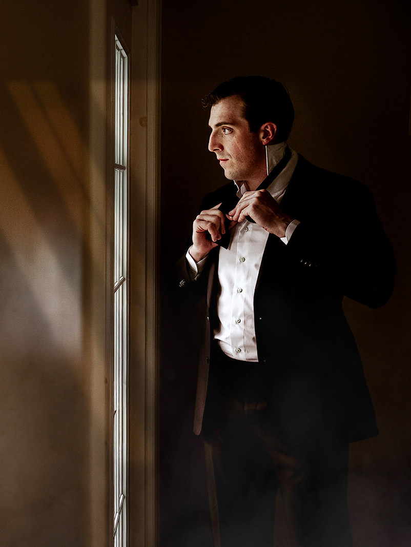 Groom getting ready by the window light at Ardington House.